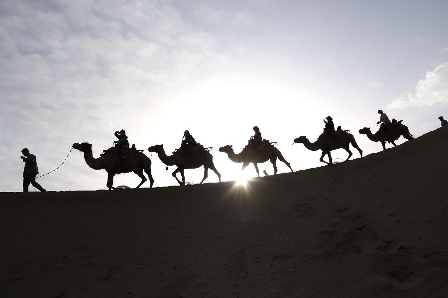 La fotografía muestra a turistas montando en camellos en la montaña Mingsha en Dunhuang en la provincia de Gansu, oeste de China el 12 de julio. Con la llegada de vacaciones de verano, Dunhuang registra recientemente un auge de turismo. 