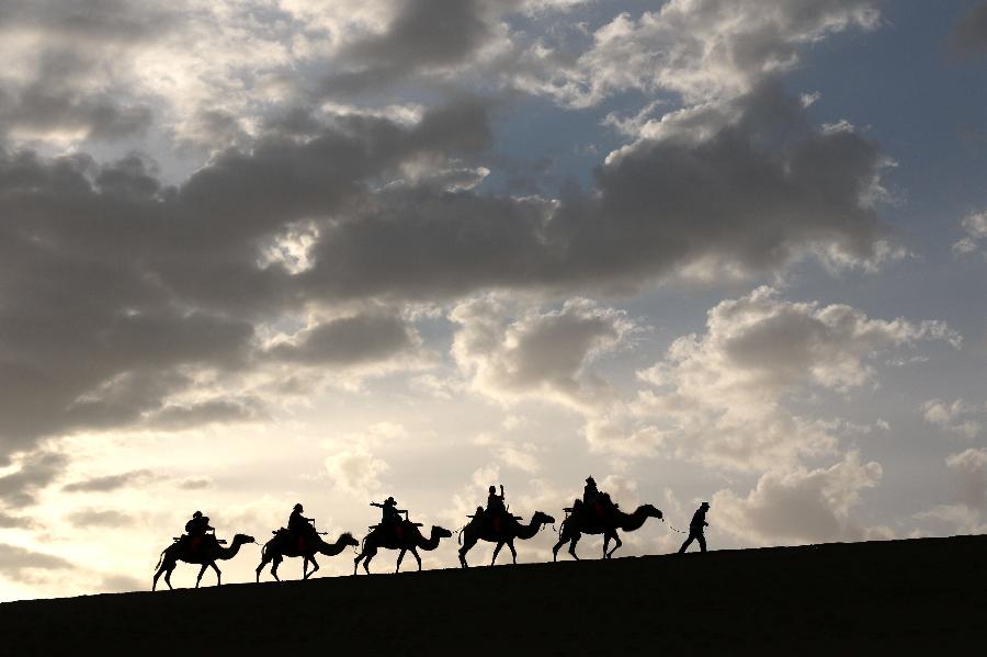 La fotografía muestra a turistas montando en camellos en la montaña Mingsha en Dunhuang en la provincia de Gansu, oeste de China el 12 de julio. Con la llegada de vacaciones de verano, Dunhuang registra recientemente un auge de turismo. 