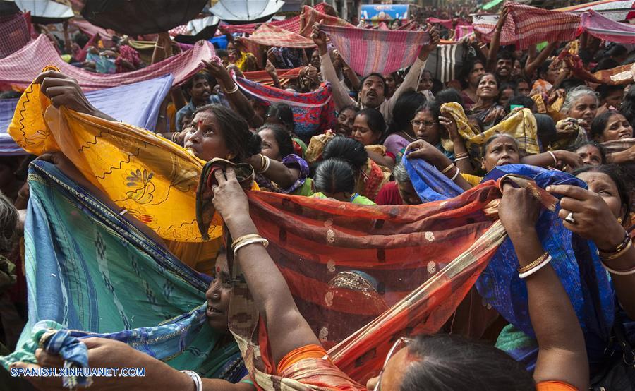 Una devota india extiende su sari para recolectar arroz para celebrar el ritual de Annakut, que consiste en pedir arroz a los dioses durante el segundo día del festival de Diwali en Culcata, India. Diwali, el festival hindú de la luz, simboliza la vuelta del diós indio Rama después de su triunfo sobre el rey de demonio Ravana.