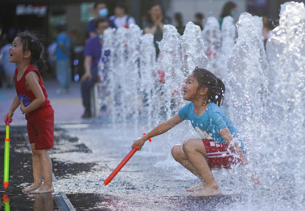 Niños se refrescan en una fuente en Beijing