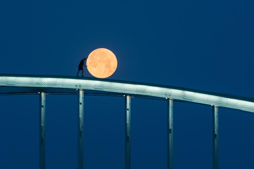 Hombre posa en lo alto de un puente ferroviario durante Luna llena en Croacia