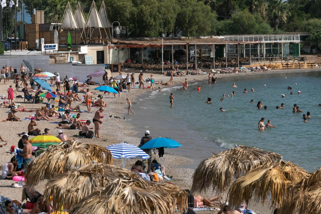 Personas disfrutan del Sol y el mar en playa de Alimos en Atenas, Grecia