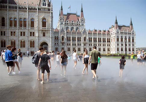 Personas se refrescan a través de los rociadores en plaza pública en Budapest
