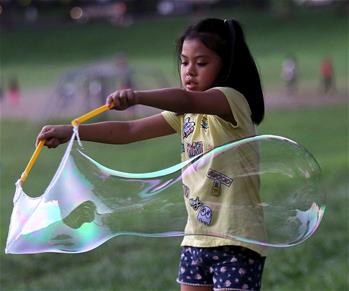 Una niña hace grandes burbujas de jabón en Quezon