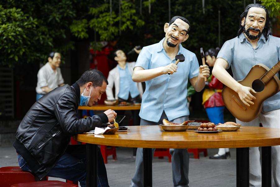 Personas comen entre estatuas en un restaurante al aire libre en Wuhan