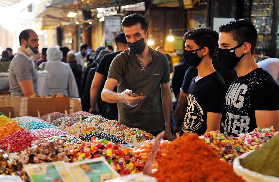 Personas realizan compras previo al festival de Eid al-Adha en Siria