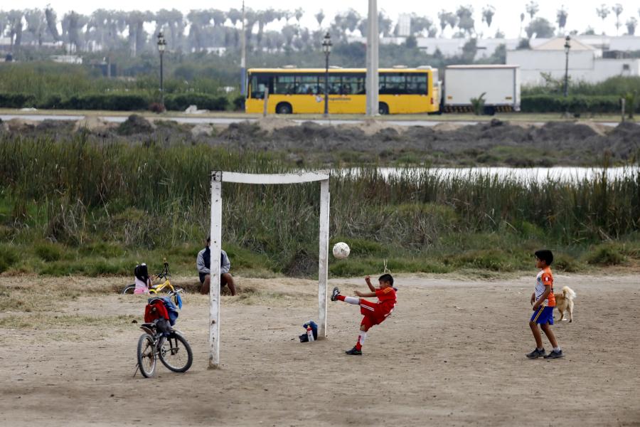 Niños juegan fútbol en cancha en distrito de Chorrillos en Lima, Perú