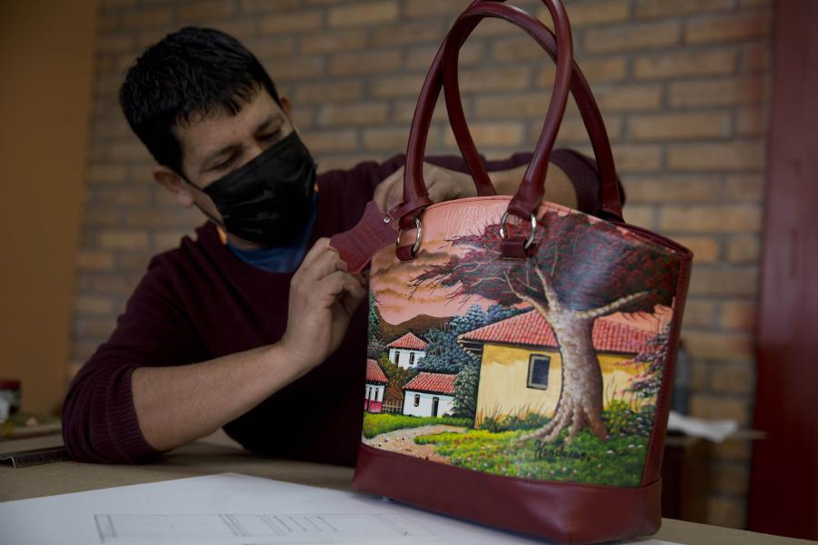 Elaboración de bolsos de cuero decorados con pinturas de artistas plásticos locales en Valle de Angeles, Honduras
