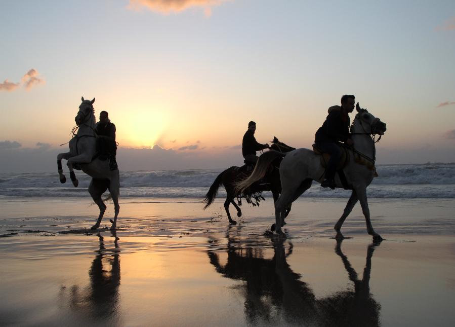Personas disfrutan de su tiempo durante el atardecer en la playa en la Ciudad de Gaza