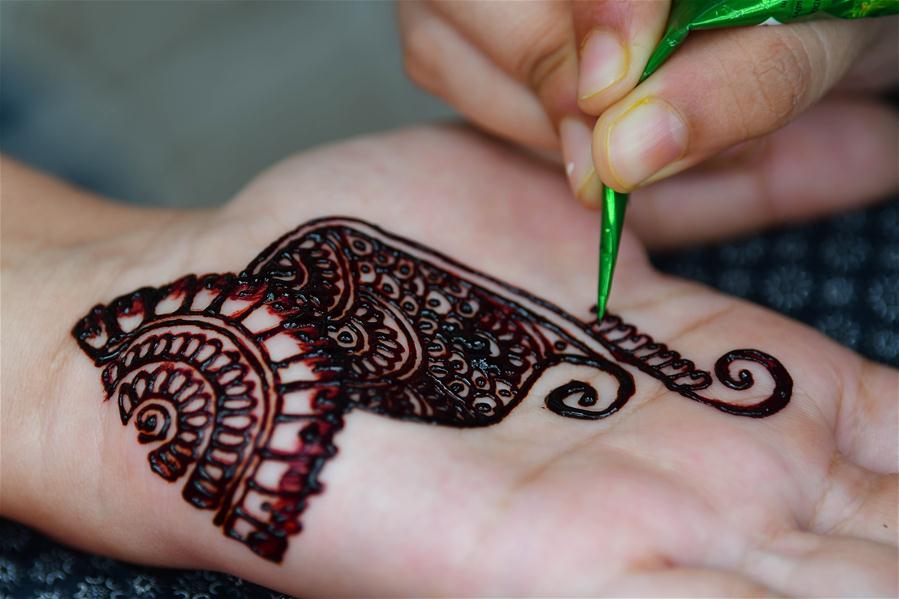 India: Niña se adorna manos con diseños tradicionales con henna